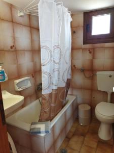 a bathroom with a tub and a toilet and a shower curtain at ANATOLI ROOMS SERIFOs in Serifos Chora