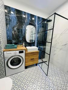 a bathroom with a washing machine and a mirror at Apartamenty Dębowa 18 in Milicz