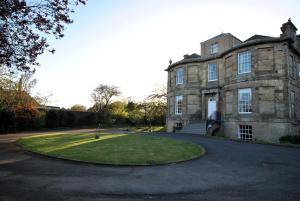 an old stone building with a grassy yard in front at Kirkmay House Apartment in Crail