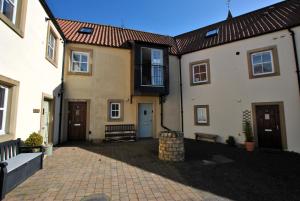 a group of buildings with a brick courtyard at Coorie Cottage- stylish townhouse Anstruther in Anstruther