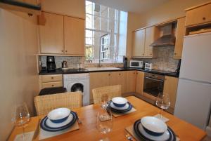 a kitchen with a wooden table with plates and wine glasses at Kirkmay House Apartment in Crail