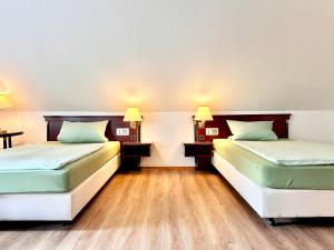 zwei Betten in einem Zimmer mit Holzböden und Lampen in der Unterkunft Ferienwohnung 2-4 Pers WLAN und Parkplatz, HDZ und Kliniken in der Nähe, direkt an der A2 und A30 gelegen in Löhne + 3 Fotos