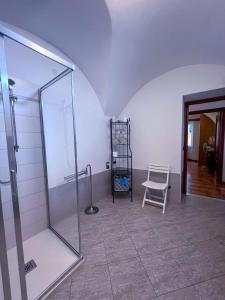 a bathroom with a glass shower and a chair at Orchidea in Finale Ligure