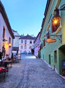 an empty alley with tables and chairs in a city at The Throne - M Museum Hotel in Sighişoara