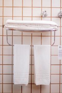 Duas toalhas brancas penduradas num cabide na casa de banho em Ilha Flat Hotel em Ilhabela