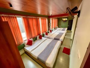 eine Reihe von Betten in einem Zimmer mit Fenstern in der Unterkunft Hotel City Palace in Udagamandalam
