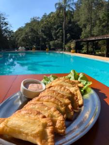 Un plato de comida en una mesa junto a una piscina. en Pousada Pedra Grande Atibaia, en Atibaia