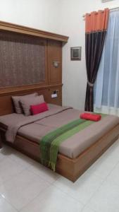 1 dormitorio con 1 cama grande con almohadas rojas y verdes en Sekar Wangi Homestay en Sleman