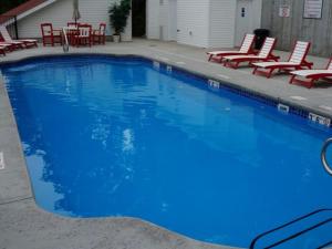 a large blue swimming pool with red chairs and tables at Waterfront Condo with Boat Slip! in Lake Ozark