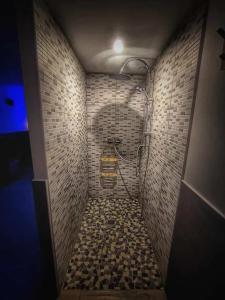 ein Bad mit einer Dusche und einer gefliesten Wand in der Unterkunft Villa de 4 chambres avec piscine privee sauna et jardin clos a La Poterie Cap d'Antifer in La Poterie-Cap-dʼAntifer