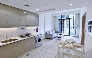Dubai Creek Budget Apartment في دبي: مطبخ وغرفة معيشة مع حوض وطاولة