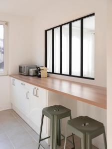 een keuken met een aanrecht met 2 krukken en een raam bij Au clair d'Augustin in Metz