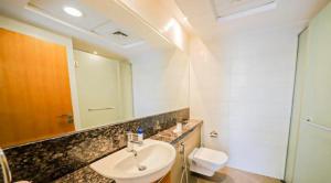 Dubai Creek Budget Apartment في دبي: حمام مع حوض ومرحاض ومرآة