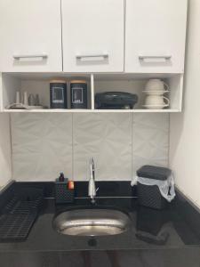 um lavatório numa cozinha com armários brancos em Pousada Bella Flor em Baía Formosa