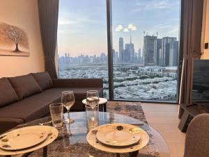 uma sala de estar com um sofá e uma mesa com copos de vinho em Dubai World Central Budget Apartments no Dubai