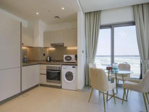 Dubai World Central Budget Apartments في دبي: مطبخ وغرفة طعام مع طاولة وكراسي