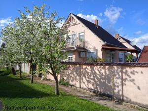 a house with a tree in front of a fence at B&aacute;nyai Apartman in Gyula