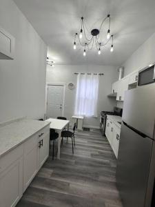 a white kitchen with a table and a refrigerator at Historic Victorian Apartment in Strathroy +9 photos