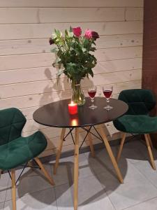 a table with two glasses of wine and a vase with flowers at Green House Panorama Karpat in Volosyanka