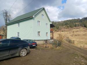 uma grande casa azul com dois carros estacionados em frente em Green House Panorama Karpat em Volosyanka