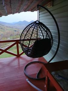 a bird cage hanging from a porch with a view at Green House Panorama Karpat in Volosyanka