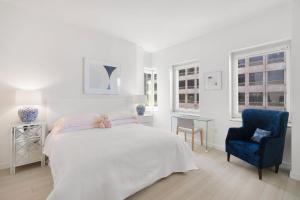 um quarto branco com uma cama e uma cadeira azul em Luxury 4 Bedroom Apartment near Times Square NYC em Nova York