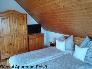 a bedroom with two beds and a flat screen tv at Bányai Apartman in Gyula