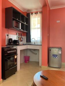 a kitchen with orange walls and a stove and a table at Todas Hotel in Kiambu