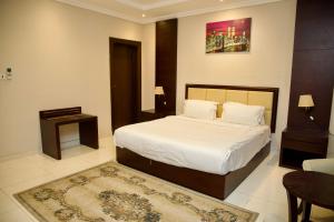 Schlafzimmer mit einem Bett, einem Tisch und einem Teppich in der Unterkunft فندق أصداء الراحة Asdaa Alraha Hotel in Dschidda