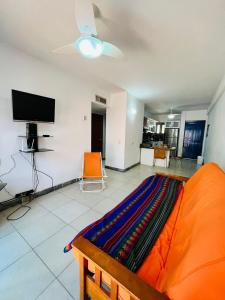 sala de estar con sofá naranja y TV de pantalla plana en Casas de Corintia en playa Moreno isla Margarita en Pampatar