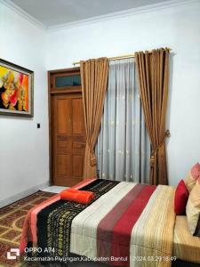 a bedroom with a bed and a window with curtains at Pringgondani Homestay in Bantul