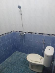 baño con aseo y pared de azulejos azules en Pringgondani Homestay, en Bantul