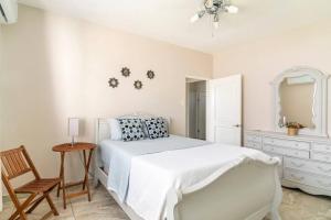 a white bedroom with a bed and a chair at Relax Home Plenty Space Near The Airport - 4min in Aguadilla