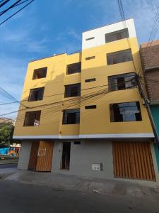 un edificio amarillo al lado de una calle en SUMAQ PUÑUY HOSTEL - LIMA AIRPORT en Lima