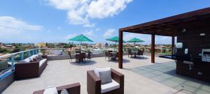 d'un balcon avec des chaises, des tables et des parasols verts. dans l'établissement Beach Way - Praia dos Carneiros, à Praia dos Carneiros