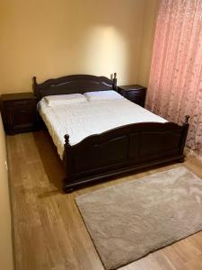 Schlafzimmer mit einem Bett mit einem Holzrahmen und einem Teppich in der Unterkunft Apartament lux 3 camere in Roman