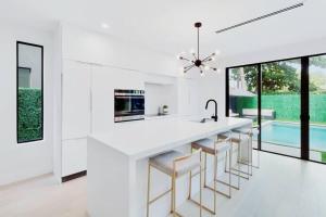 uma cozinha com um balcão branco e bancos em Luxury Villa in Design District (heated saltwater pool) em Miami