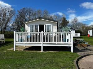 a white fence in front of a small house at Sandy Bay Caravan Getaway in Newbiggin-by-the-Sea