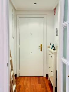 Una puerta blanca en una habitación con suelo de madera en Apartamento "Balcón del Parchís" a 200 metros de la playa en Gijón