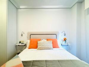 1 dormitorio con 1 cama con almohadas de color naranja en Apartamento "Balcón del Parchís" a 200 metros de la playa en Gijón