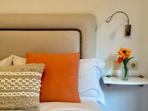 ein Bett mit einem orangenen Kissen und einer Vase mit einer Blume in der Unterkunft Apartamento "Balcón del Parchís" a 200 metros de la playa in Gijón