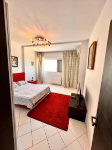 sypialnia z łóżkiem i czerwonym dywanem w obiekcie Duplex w mieście La Marsa