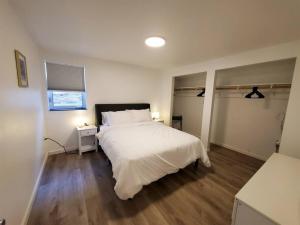 Schlafzimmer mit einem weißen Bett und Holzboden in der Unterkunft Updated Douglas Apartment, Near Downtown and Skiing in Juneau