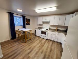 eine Küche mit weißen Schränken und einem Tisch mit Stühlen in der Unterkunft Updated Douglas Apartment, Near Downtown and Skiing in Juneau