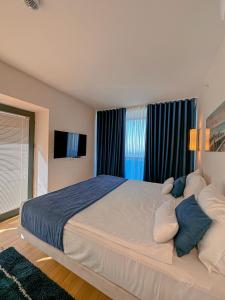 a bedroom with a large white bed with blue pillows at Luxury Batumi Hotel in Batumi