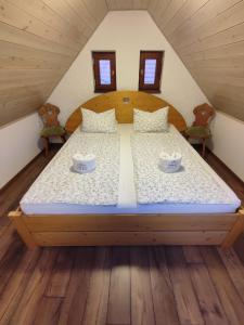 Una cama grande en un ático con dos tazas. en Szent Iván Vendégház en Tata