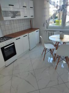 a kitchen with white appliances and a table and chairs at Kawalerka apartament ul gieldowa in Kołobrzeg