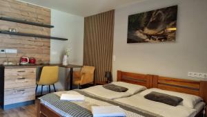 a bedroom with two beds and a desk and a table at Apartmány Mlynky - Slovenský raj in Mlynky 