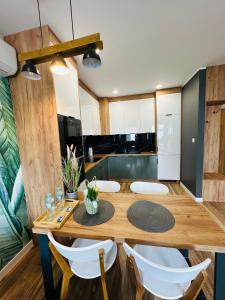 une salle à manger avec une table en bois et des chaises blanches dans l'établissement Apartamenty Dębowa 10, à Milicz