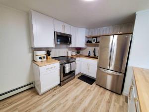 a kitchen with white cabinets and a stainless steel refrigerator at Updated Douglas Apartment, Close to Sandy Beach in Juneau